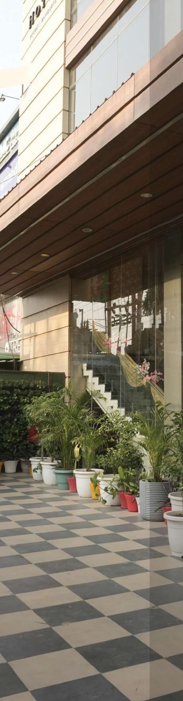 Nakshatra Hotel Exterior Walkway with Checkered Tiles and Lush Greenery